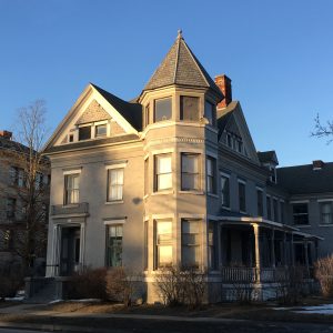 tan house with tower and side porch